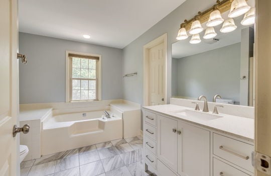 primary bathroom, tile flooring, sink, closet, toilet, tub