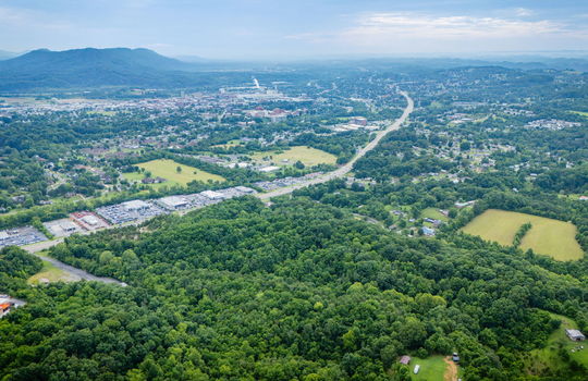 aerial photo, undeveloped land, 48+/- acres, commercial land for sale, trees, neighboring businesses, stone drive, mountain views, 1100'+ Road Frontage