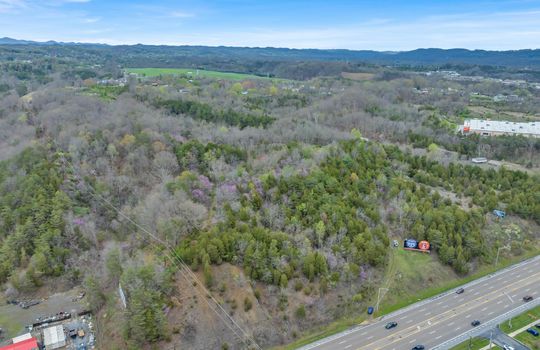 aerial photo, undeveloped land, 48+/- acres, commercial land for sale, trees, neighboring businesses, stone drive, mountain views, 1100'+ Road Frontage