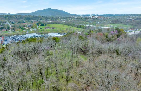 undeveloped land, aerial photo, trees, stone drive, neighboring businesses, mountain views, 1100'+ of road frontage