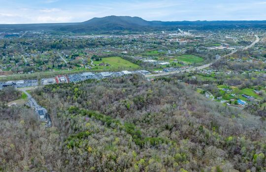 undeveloped land, aerial photo, trees, stone drive, neighboring businesses, mountain views, 1100'+ of road frontage