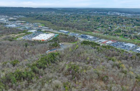 undeveloped land, aerial photo, trees, stone drive, neighboring businesses, mountain views, 1100'+ of road frontage