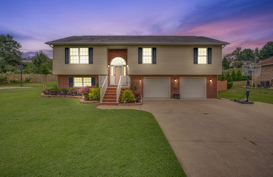Twilight photo, front yard, concrete driveway, brick stairs to front door, landscaping, brick, vinyl siding, two car garage, garage doors