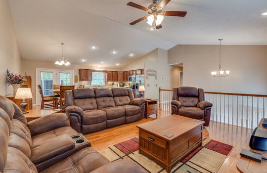 Open floor plan, living room, dining room, kitchen, hardwood flooring, recessed lighting, ceiling fan, chandeliers, door to back deck