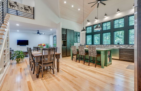 kitchen, kitchen island, commercial grade appliances, refrigerator, oven/range, microwave, dishwasher, kitchen island, windows, cabinets, tile backsplash, granite countertops, hardwood flooring, open concept to living room, and dining space