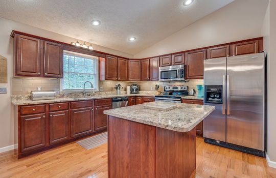 Kitchen, kitchen island, countertops, granite countertops, cabinets, sink, window above sink, dishwasher, built-in microwave, oven/range, refrigerator, hardwood flooring, recessed lighting