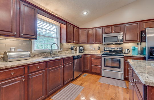 Kitchen, kitchen island, countertops, granite countertops, cabinets, sink, window above sink, dishwasher, built-in microwave, oven/range, refrigerator, hardwood flooring, recessed lighting