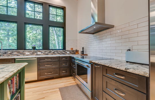 main home kitchen, stove/oven, range hood, tile backsplash, windows, dishwasher, cabinets, kitchen island, granite countertops, hardwood flooring