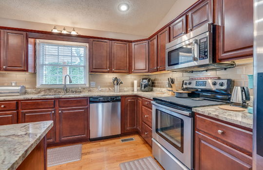 Kitchen, kitchen island, countertops, granite countertops, cabinets, sink, window above sink, dishwasher, built-in microwave, oven/range, refrigerator, hardwood flooring, recessed lighting