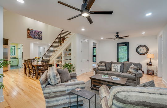 living room, open concept to kitchen and dining, stairs to upper level, doorway to lower level, hardwood flooring, ceiling fans, recessed lighting