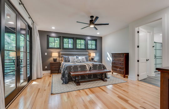 bedroom, double doors to back deck, ceiling fan, windows, hardwood flooring, door to primary ensuite bathroom