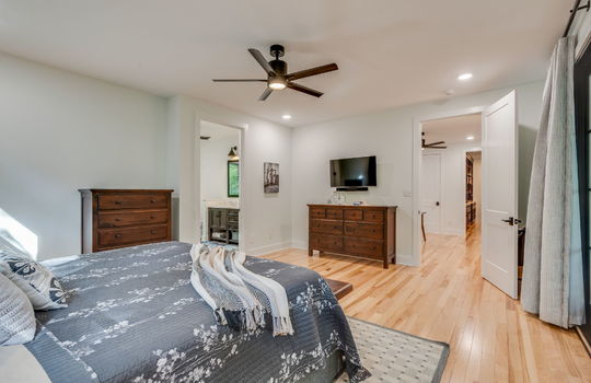 primary bedroom, ceiling fan, hardwood flooring, door to hallway, door to primary ensuite bath