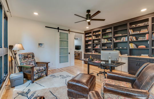 office, built-in shelving, hardwood flooring, ceiling fan, barn door, windows, hardwood flooring