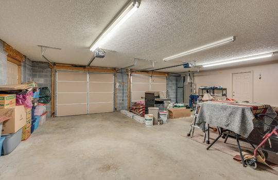 garage, two car garage, exterior door, interior door, garage doors, concrete flooring, fluorescent lighting