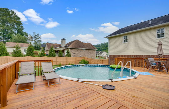 Pool with deck surround, fully fenced back yard, back of home, vinyl siding, brick
