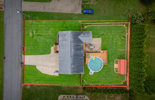 overhead aerial view of property, property outline, driveway, roof, front steps, back yard, covered back deck, patio pavers, pool with deck, storage shed, landscaping
