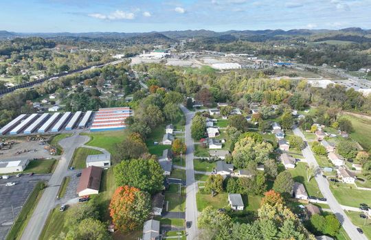 aerial view of property, road, neighboring homes, neighboring businesses, mountains