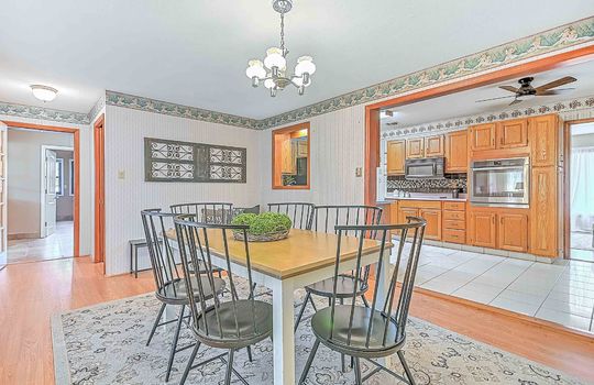 Dining room, doorway into kitchen, chandelier, hardwood flooring