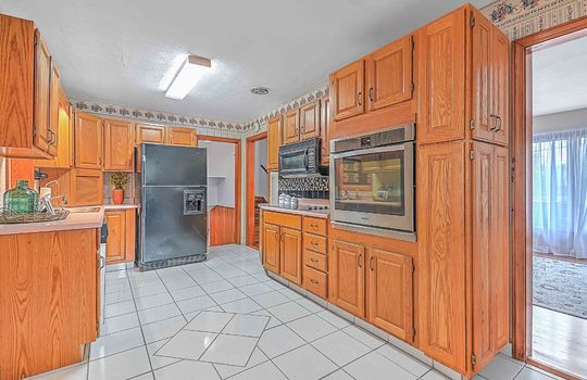 kitchen, tile flooring, cabinets, countertops, refrigerator, built-in microwave, wall oven, cooktop, fluorescent lighting
