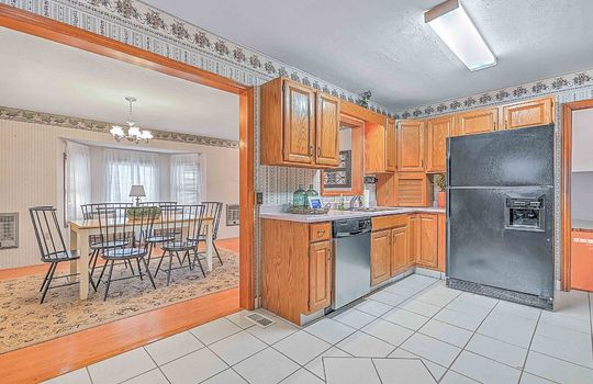 kitchen, tile flooring, cabinets, countertops, refrigerator, dishwasher, sink, fluorescent lighting, doorway to formal dining room