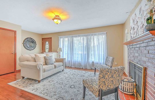 living room, large windows, hardwood flooring, fireplace, coat closet, front door, entryway