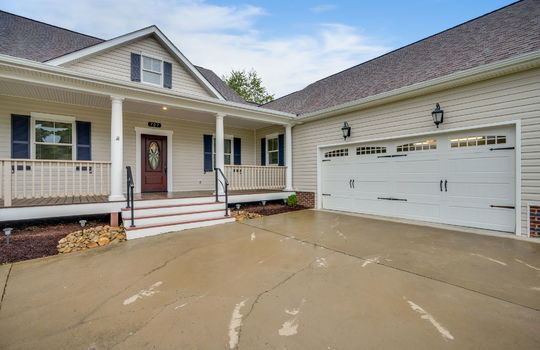 cape cod style home, concrete driveway, covered front porch, front door, garage doors, 2 car garage, front door