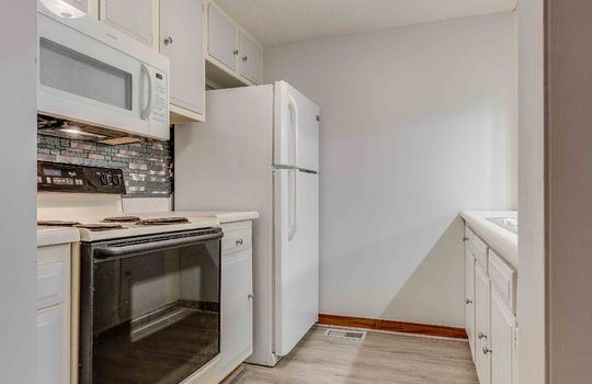 kitchen, sink, cabinets, countertops, refrigerator, oven/range, built-in microwave, vinyl flooring