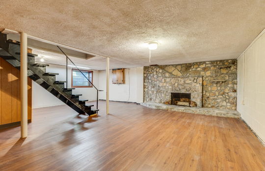 basement/lower level, stone fireplace, stairs to upper level, window, laminate flooring