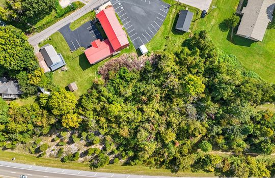 aerial view of property, wooded property, road nearby, businesses nearby, homes nearby