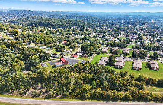 aerial view of property, nearby homes, nearby businesses, wooded property, mountains