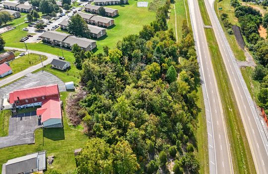 aerial view of property, interstate nearby, wooded property, nearby homes