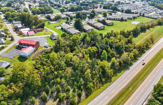 aerial view of property, interstate nearby, wooded property, nearby homes/businesses