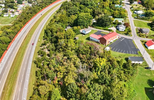Aerial view of property, wooded property, interstate, nearby homes/businesses