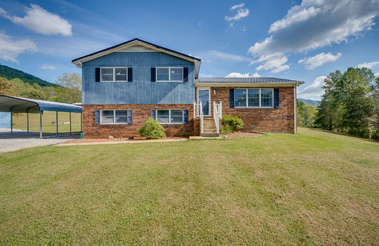 front of home, brick, wood siding, stairs to front door, front door, landscaping, carport, sidewalk, gravel driveway, mountain views