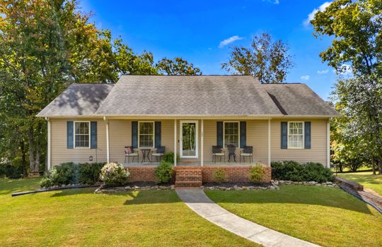 ranch style home, covered front porch, front door, storm door, sidewalk, landscaping, front yard, trees