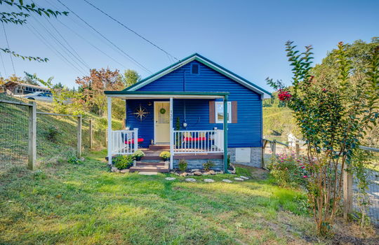 Cottage, covered front porch, front door, landscaping, fencing, vinyl siding
