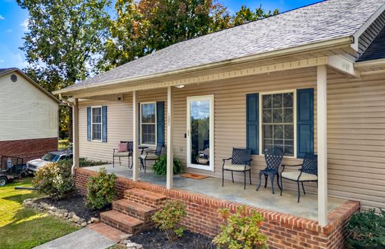 ranch style home, covered front porch, concrete porch, front door, storm door, windows, vinyl siding, shingle roof, landscaping