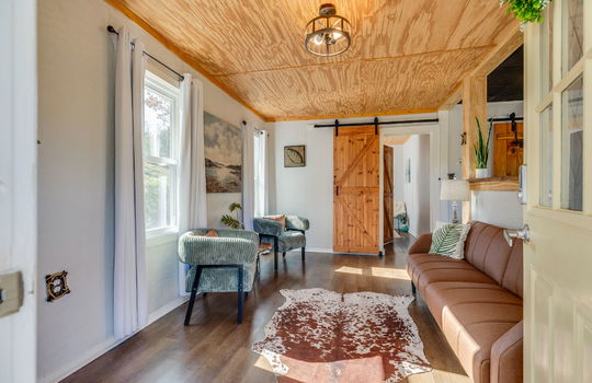 living room, luxury vinyl flooring, beadboard ceiling, window, barn door