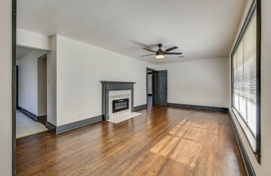 living room, fireplace, ceiling fan, door to kitchen, large windows