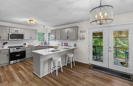 kitchen, bar seating, door to back deck, eat-in kitchen, dining space, luxury vinyl flooring, cabinets, granite countertops, sink, built-in microwave, stainless steel appliances, stove, dishwasher, tile backsplash, windows