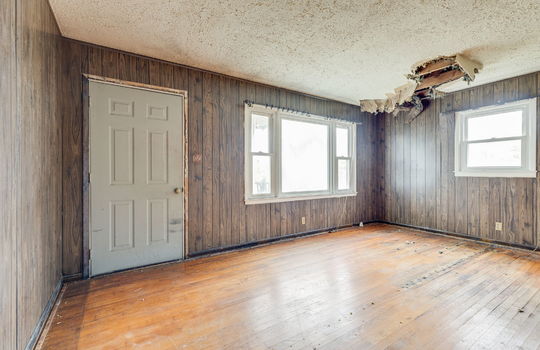 living room, fixer upper, ceiling damage, windows, front door, hardwood flooring, paneling walls