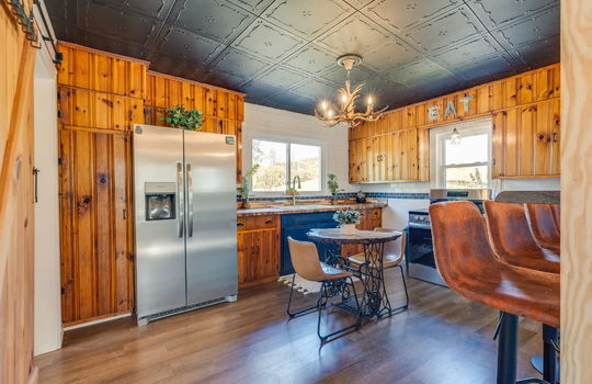 kitchen, stainless appliances, refrigerator, stove, sink, wood cabinets, butcher block countertop, luxury vinyl flooring, bar seating