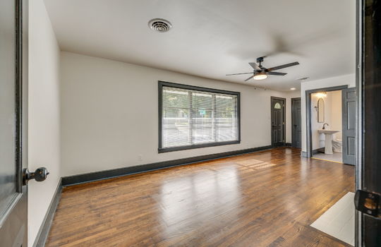 living room, hardwood flooring, ceiling fan, door to bathroom, large window, front door,