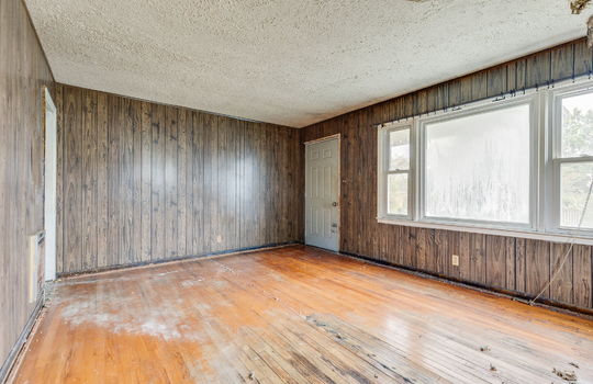 living room, paneling walls, hardwood flooring, front door, large windows