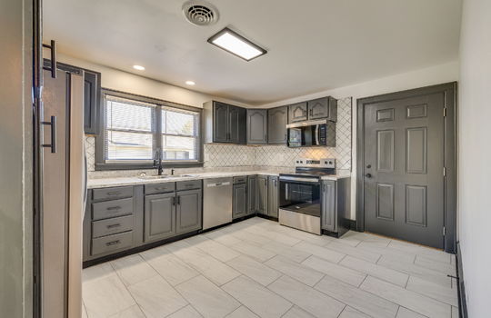 kitchen, tile backsplash, cabinets, countertops, tile flooring, stainless appliances, refrigerator, dishwasher, built-in microwave, oven/range, sink, window above sink, exterior door