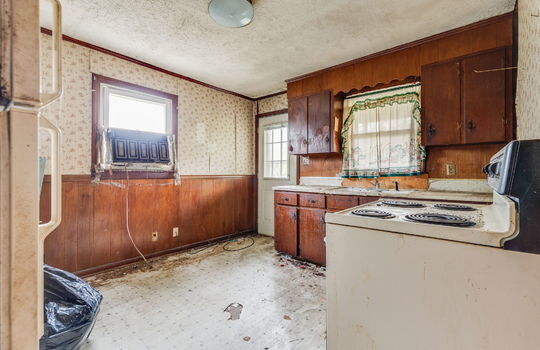 kitchen, fixer upper, cabinets, sink, refrigerator, oven/range, vinyl flooring, paneling and wallpaper walls, exterior door