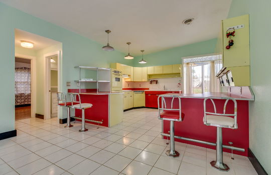 kitchen, tile flooring, bar seating, metal cabinets, wall ovens, cooktop, dishwasher, sink