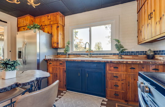 kitchen, subway tile backsplash, wood cabinetry, butcher block countertops, stainless steel refrigerator, stainless steel stove, luxury vinyl flooring, window above sink