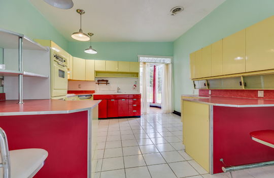 kitchen, metal cabinets, bar seating, wall ovens, dishwasher, sink, doorway, tile flooring