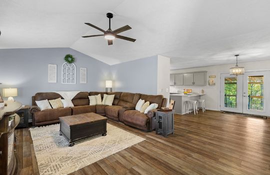 living room, vaulted ceiling, ceiling fan, laminate flooring, open floorplan, dining area, kitchen, door to back deck